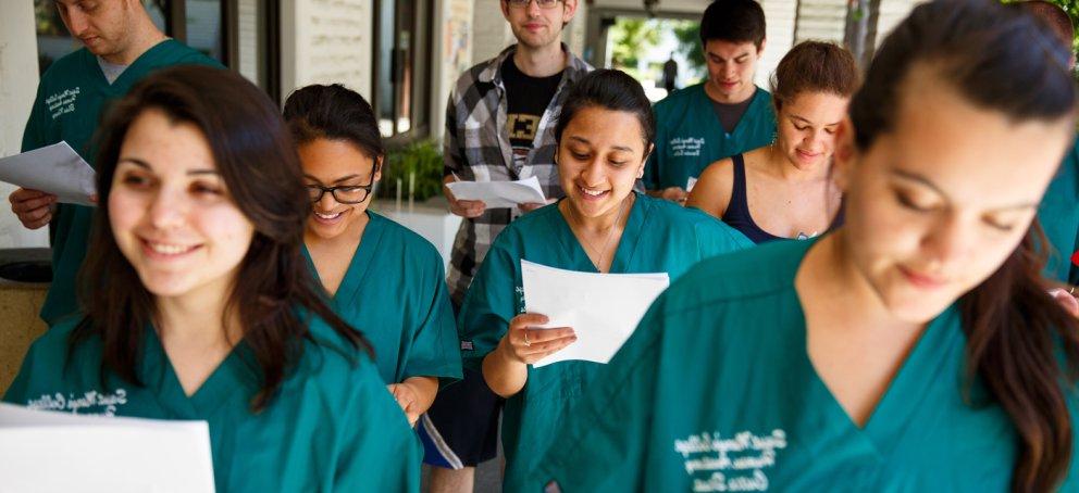 Students looking at papers while wearing scrubs and walking down the hall