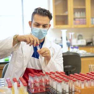 一名男实验室学生在实验室里处理装在小瓶里的样品