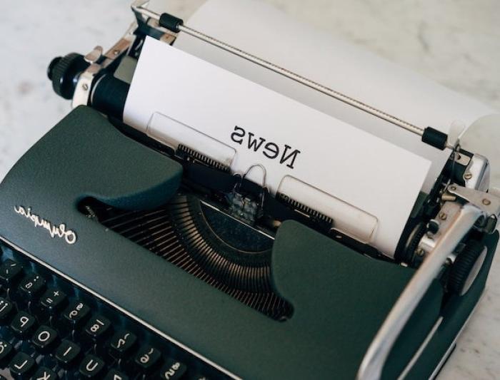 a typewriter with a sheet of paper reading "news"